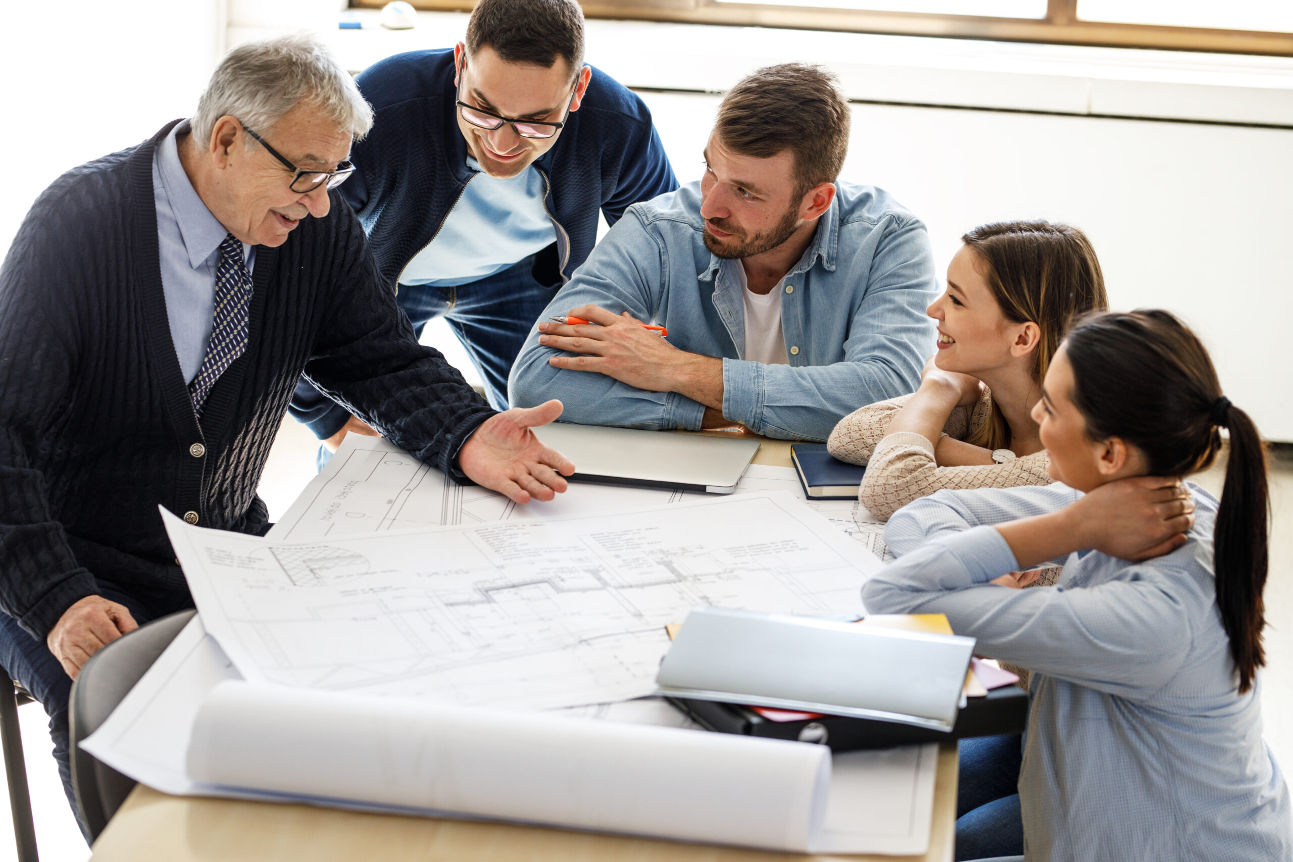 Team of two quantity surveyors looking at building drawings and explaining them to a family