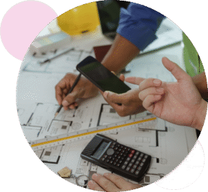 Two sets of hands of builders working on floorplans with a phone on the table, pen in hand and a calculator on the desk