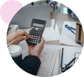 QS using a calculator with drawings, laptop and building drawings visible on table