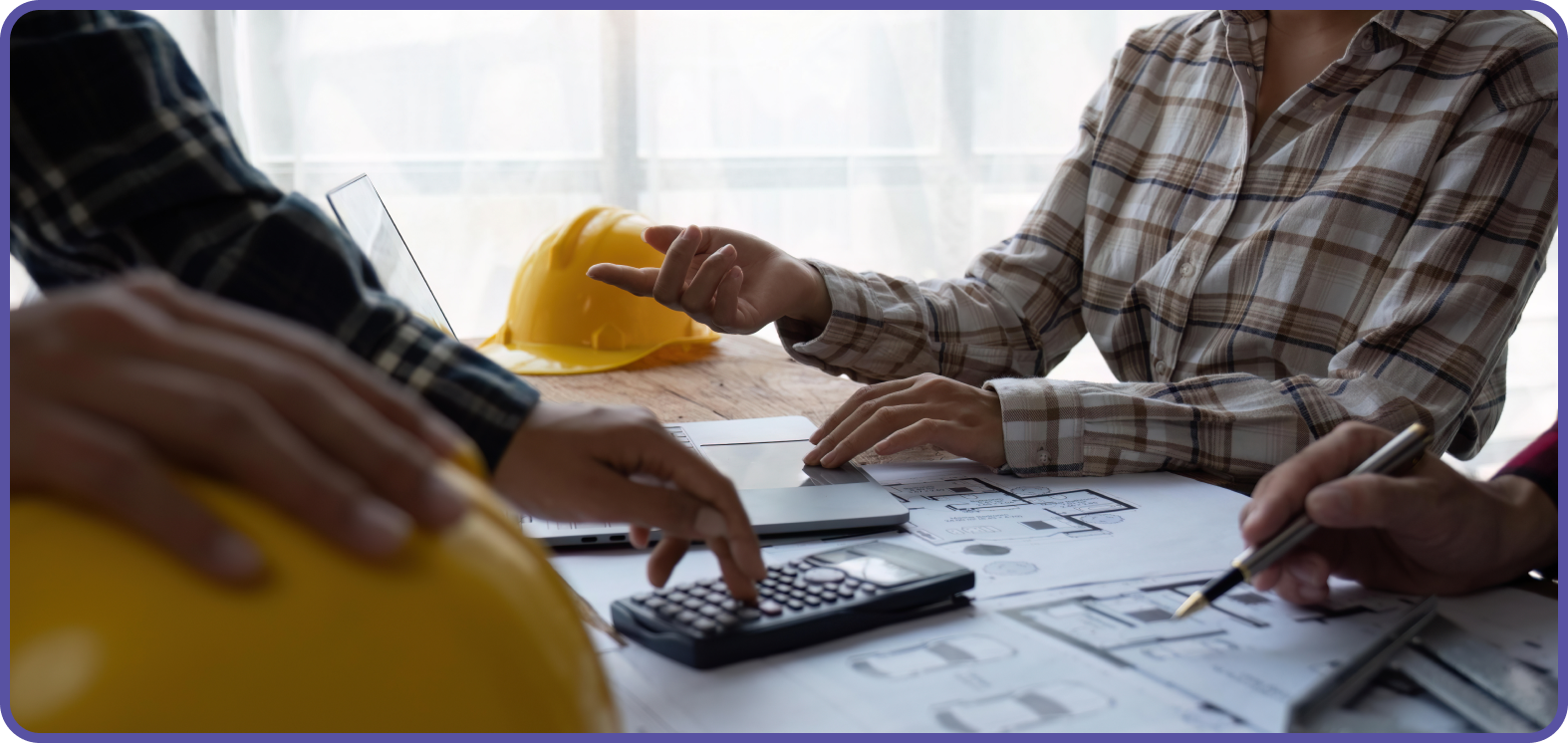 Two people looking over drawings from a building project using a calculator
